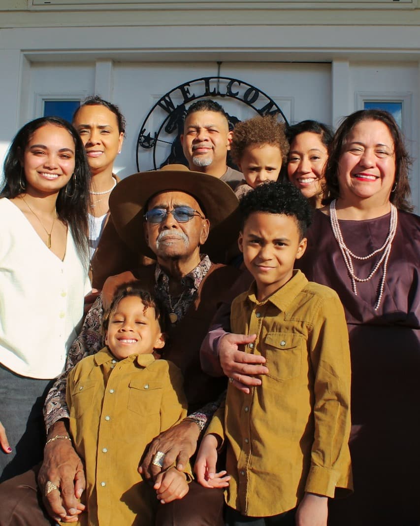 A multigenerational family gathered together on their front porch, smiling